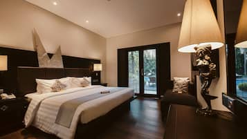 A modern hotel room with a large bed, a nightstand, a desk, and a statue.