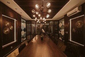 A modern dining area with a long wooden table, patterned walls, and a unique chandelier.
