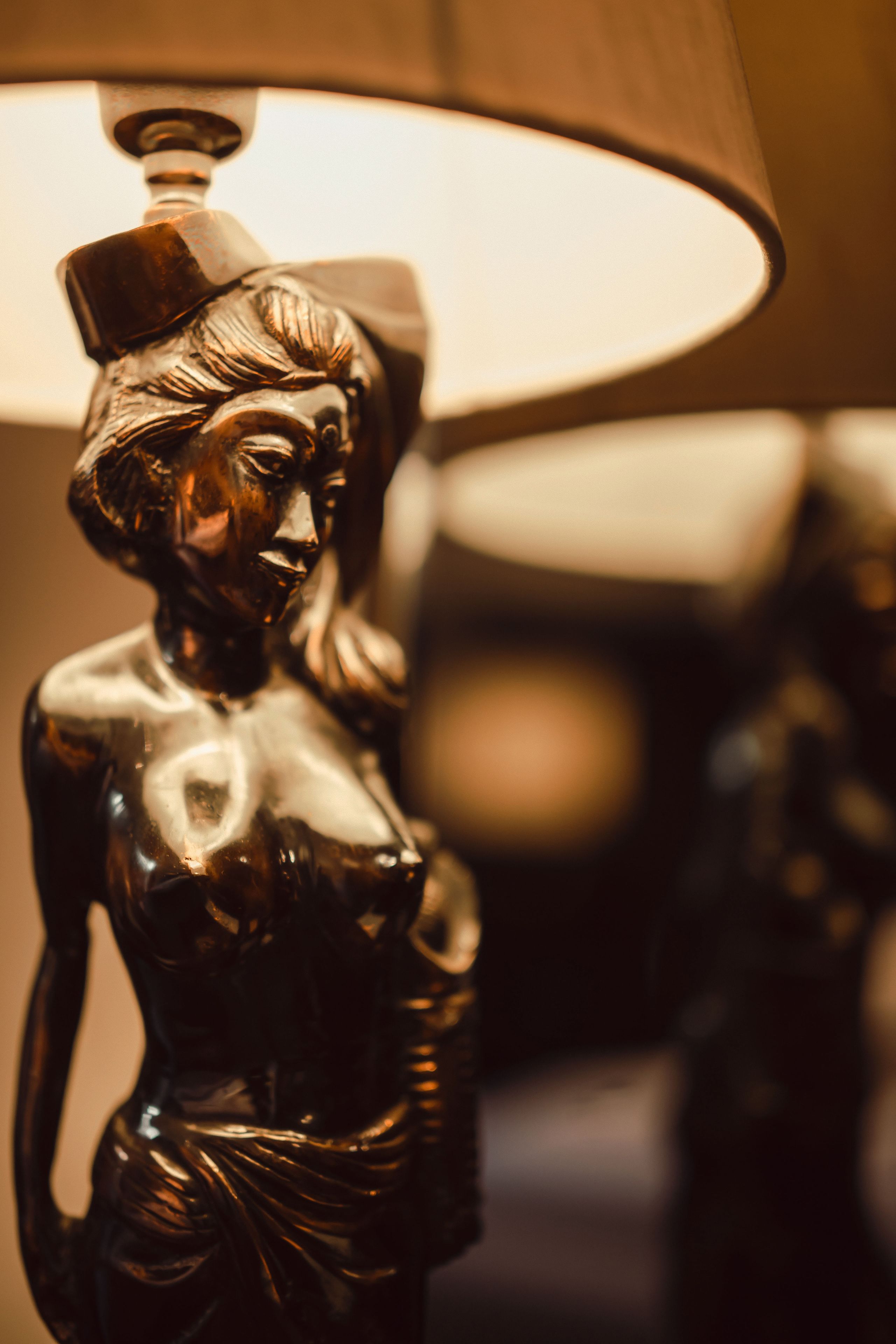 A close-up of a bronze statue with a lamp in the background.