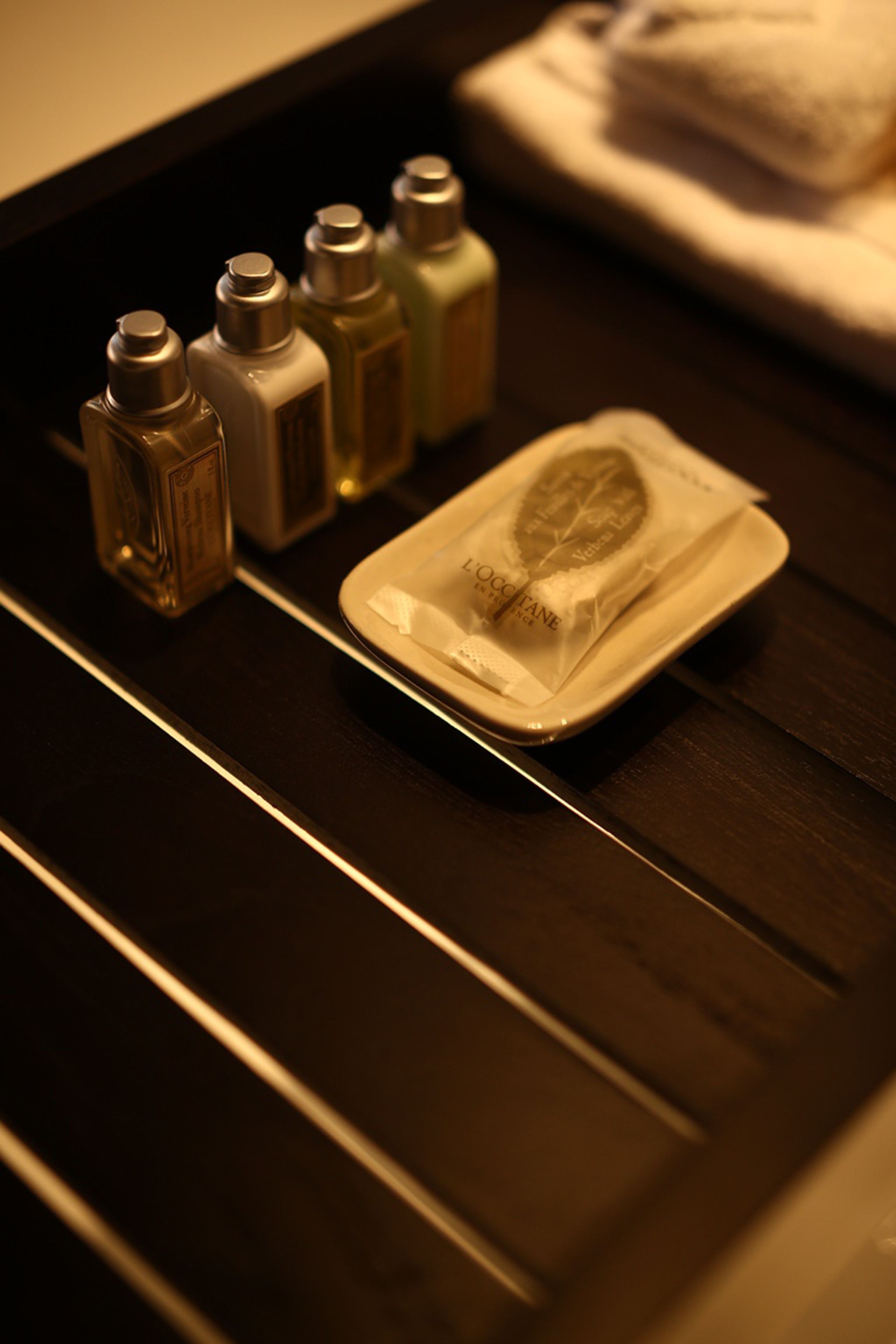 A tray with toiletries including a tissue, a small bottle, and a container with a leaf design.