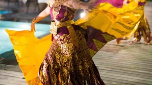A traditional dance performance by two dancers in elaborate costumes with a pool and outdoor seating in the background. - The Vira Bali Boutique Hotel & Suite (Kuta)