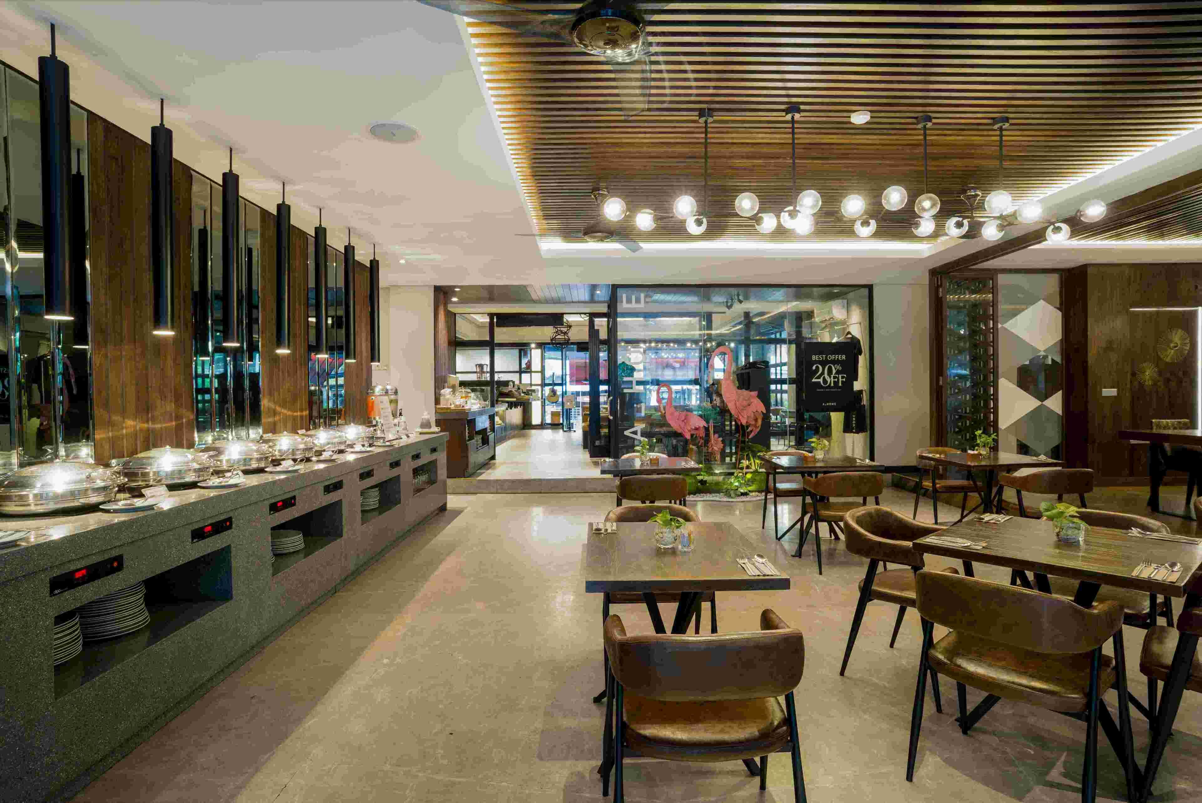 A modern dining area with a buffet setup, multiple seating arrangements, and a contemporary ceiling design.