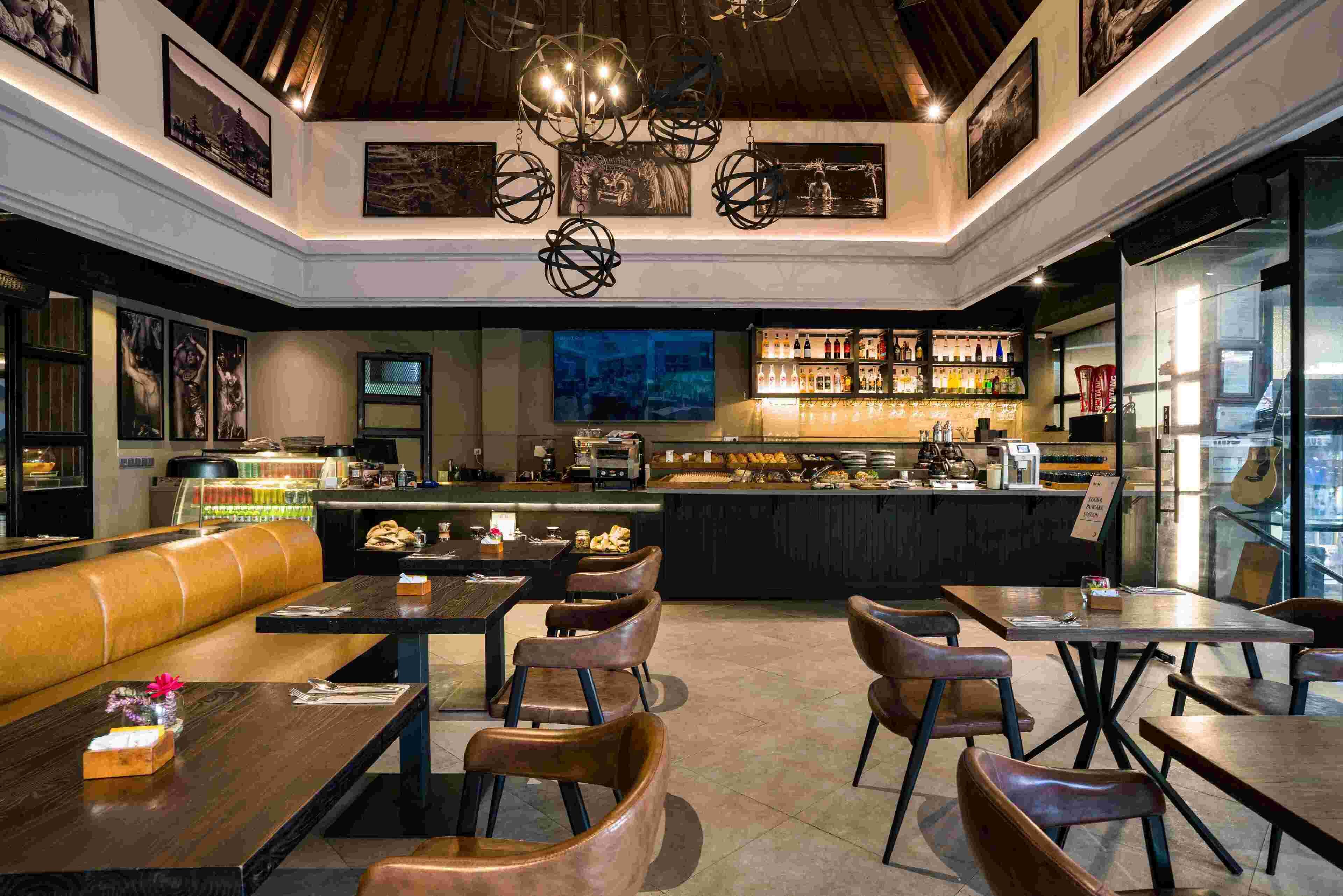 A modern bar area with seating, a counter with a variety of bottles, and artwork on the walls.