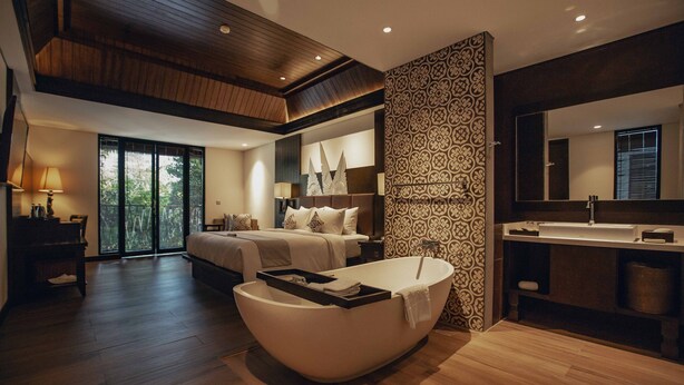 A modern bedroom with a large bed, a bathtub, a vanity with a mirror, and a large window. - The Vira Bali Boutique Hotel & Suite (Kuta)