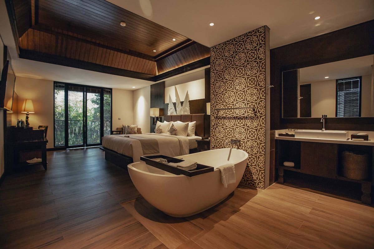 Un dormitorio moderno con una cama grande, una bañera, un tocador con espejo y un amplio ventanal.