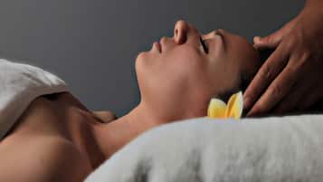 Una persona recostada con una toalla cubriendo la parte superior del cuerpo, recibiendo un masaje.