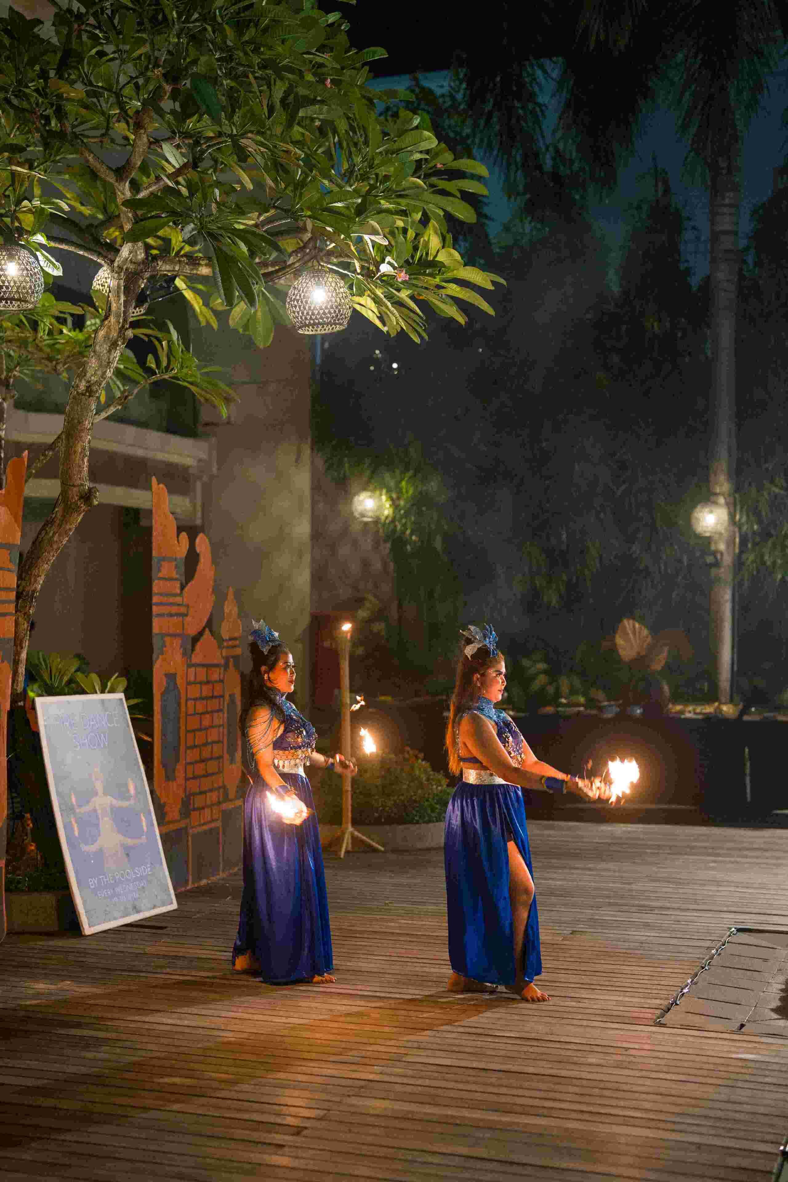 Two individuals performing with fire torches in an outdoor setting at night.