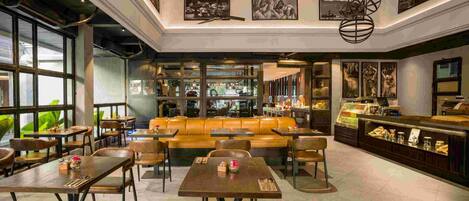 A modern restaurant with a central seating area, a bar, and large windows.