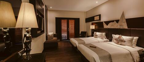A hotel room with two beds, a desk, a chair, a lamp, and a decorative wall piece.