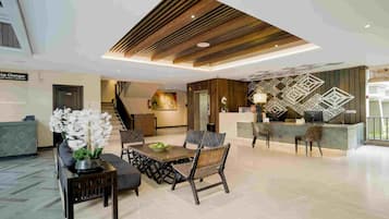 A modern lobby with a reception desk, seating area, and a staircase.