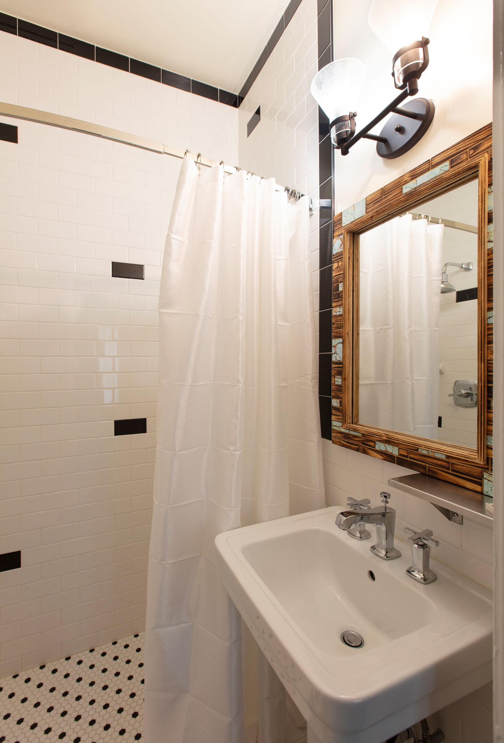 A bathroom with a shower, a sink, and a mirror.