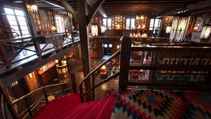 A multi-level hotel interior with a red carpeted staircase, wooden railings, and a patterned carpet. - Hotel El Rancho  (Gallup)