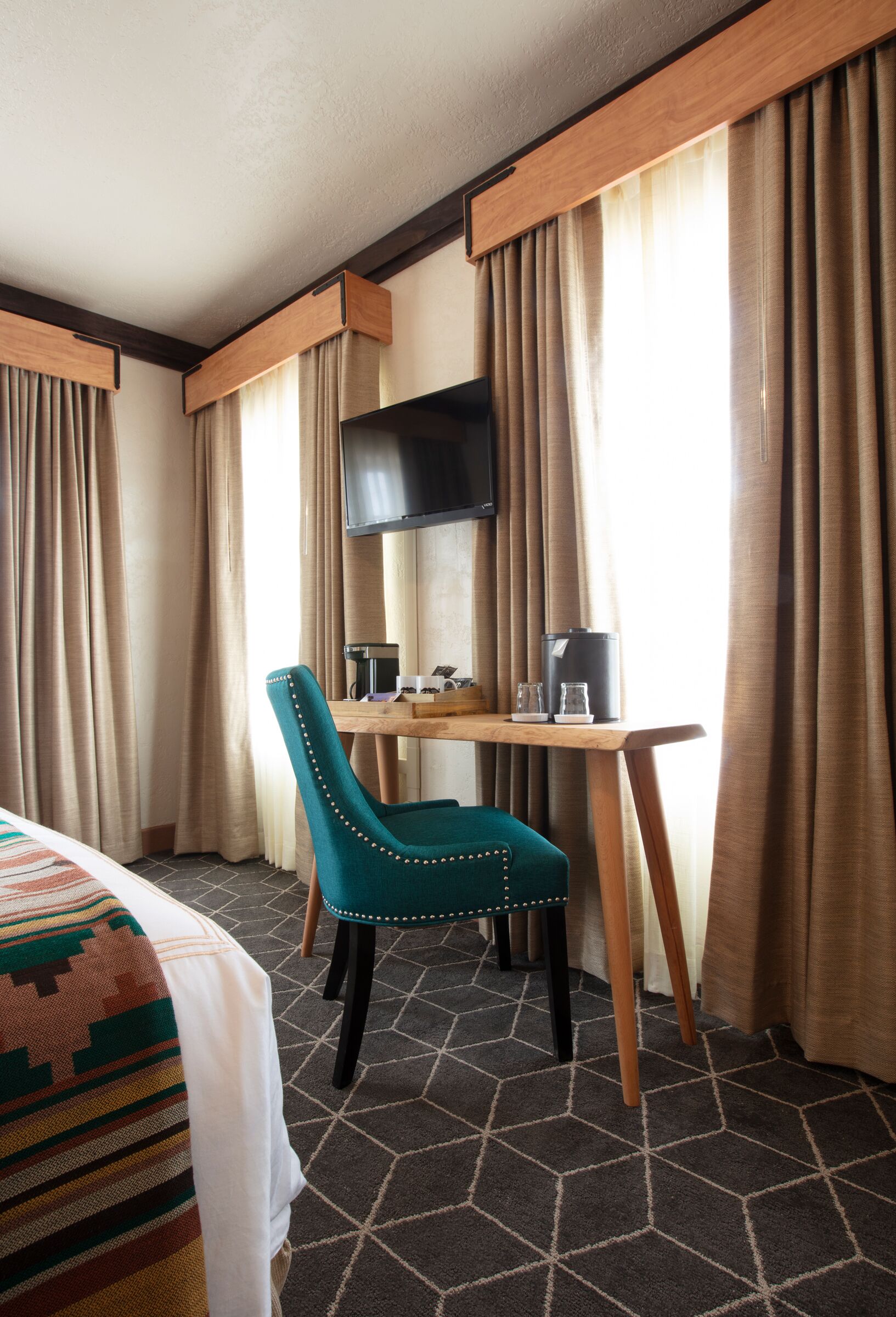 A hotel room with a bed, a desk with a chair, a television, and a coffee maker.