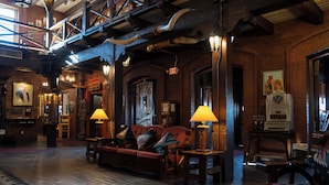A lobby with a wooden floor, a red sofa, and a lamp. - Hotel El Rancho  (Gallup)