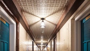 A long hallway with patterned carpet, wooden beams, and blue doors. - Hotel El Rancho  (Gallup)