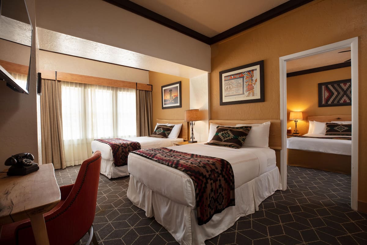 A hotel room with two beds, a desk with a telephone, and a chair.
