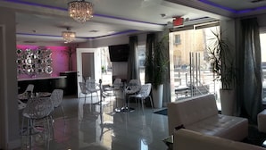 A modern hotel lobby with a glass dining area, white sofas, a chandelier, and a large window with a view of the street. - Hollywood VIP Hotel (Los Angeles)