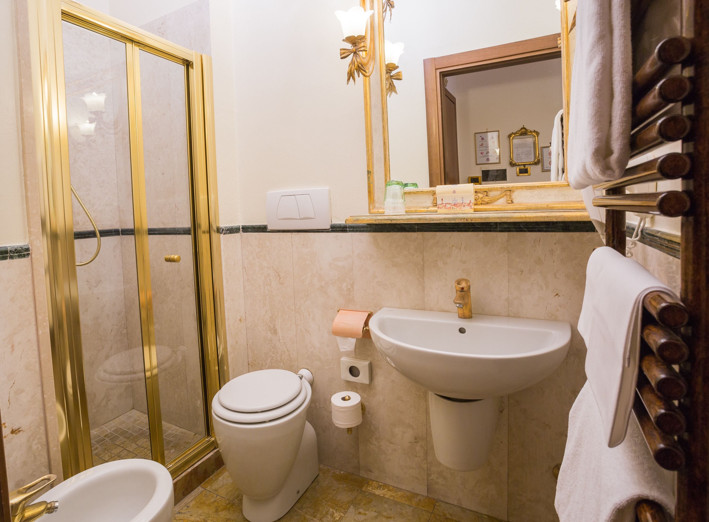 A bathroom with a glass-enclosed shower, a toilet, a sink, and a towel rack.