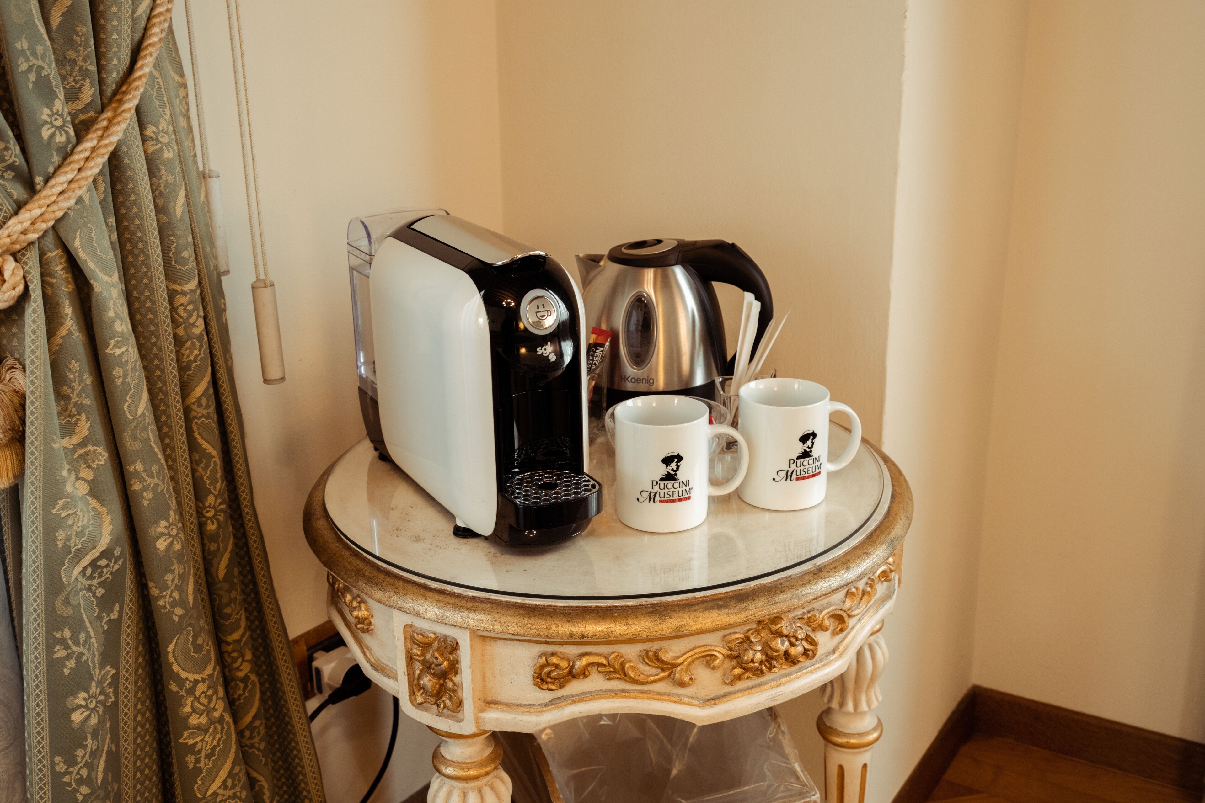 A coffee maker, two mugs, and a toaster on a small table.