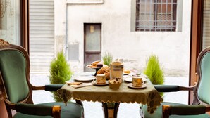 A table set for breakfast with a view of a narrow street and buildings. - Palazzo Alexander Hotel (Lucca)