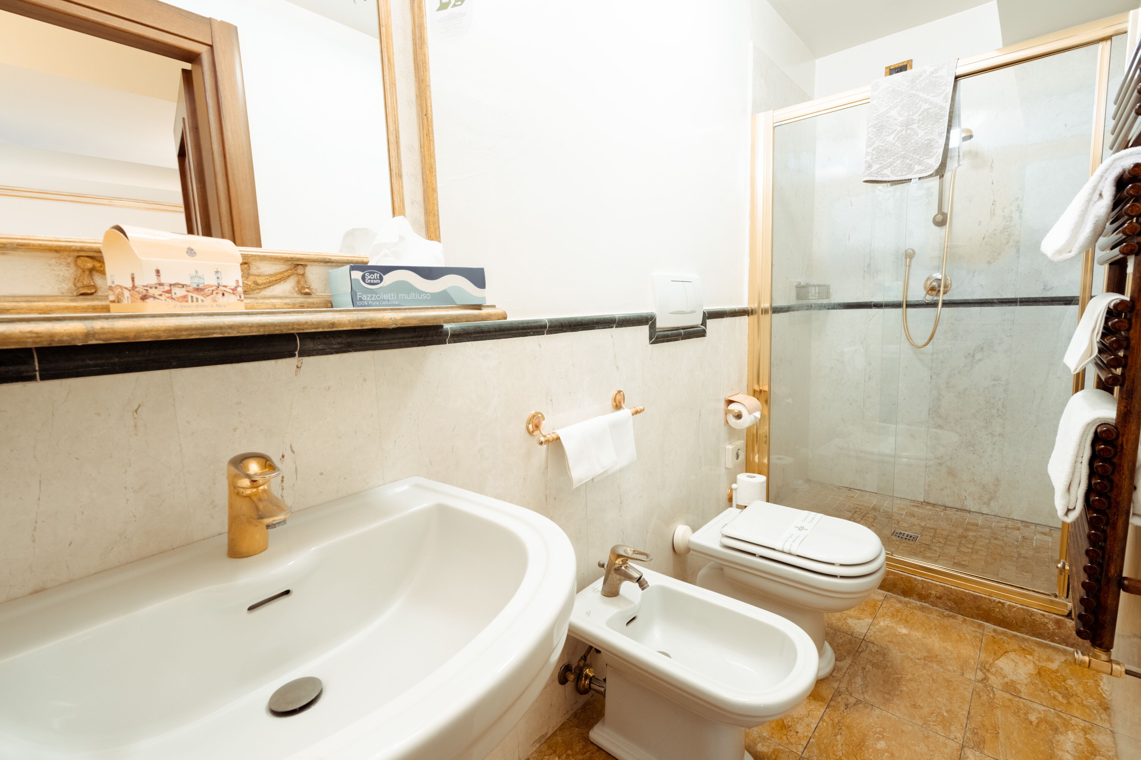 A bathroom with a large sink, a bidet, a toilet, and a glass-enclosed shower area.