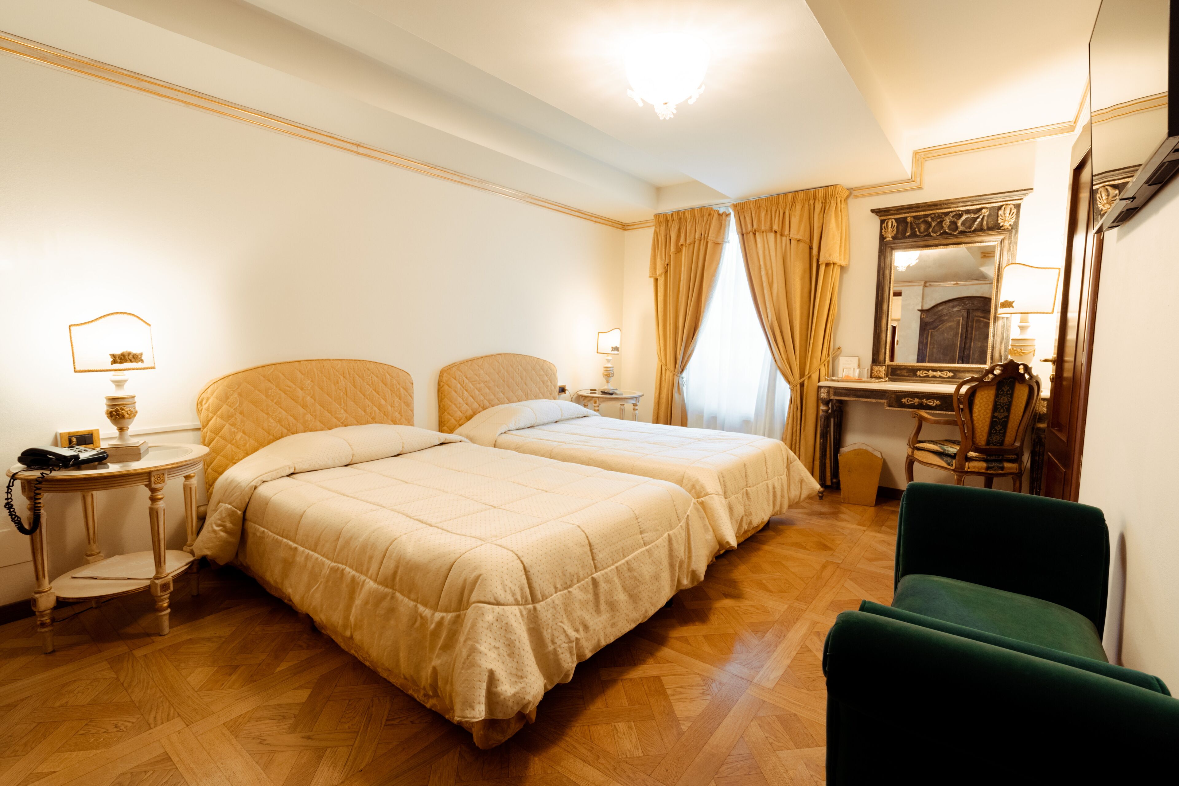 A hotel room with two beds, a desk, a chair, a mirror, and a telephone.