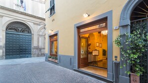 A building with a large arched entrance, a number '48' sign, and a potted plant outside. - Palazzo Alexander Hotel (Lucca)