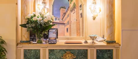 A reception desk with a marble counter, a clock, and a framed painting of a cityscape.