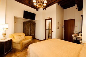 Una camera da letto con un letto grande, un armadio in legno, una televisione a muro e un lampadario.
