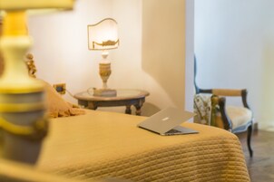Un letto con un portatile, una lampada e una sedia in una stanza dal design essenziale e pulito.