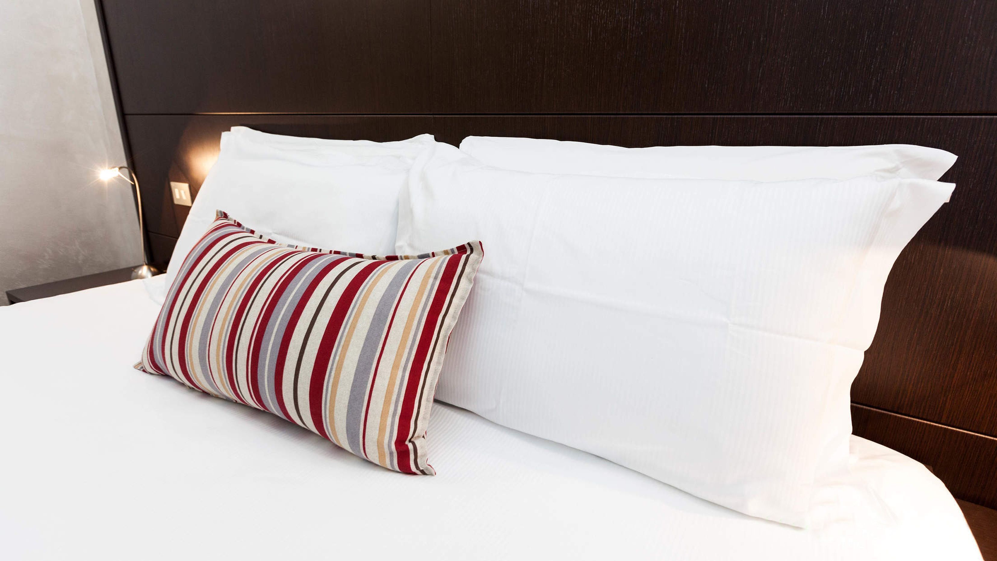 Un lit bien fait, avec des draps blancs et un oreiller à rayures.
