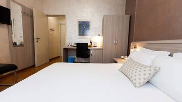 Una camera d'albergo con un letto, una scrivania, una sedia, un telefono e un quadro appeso al muro.