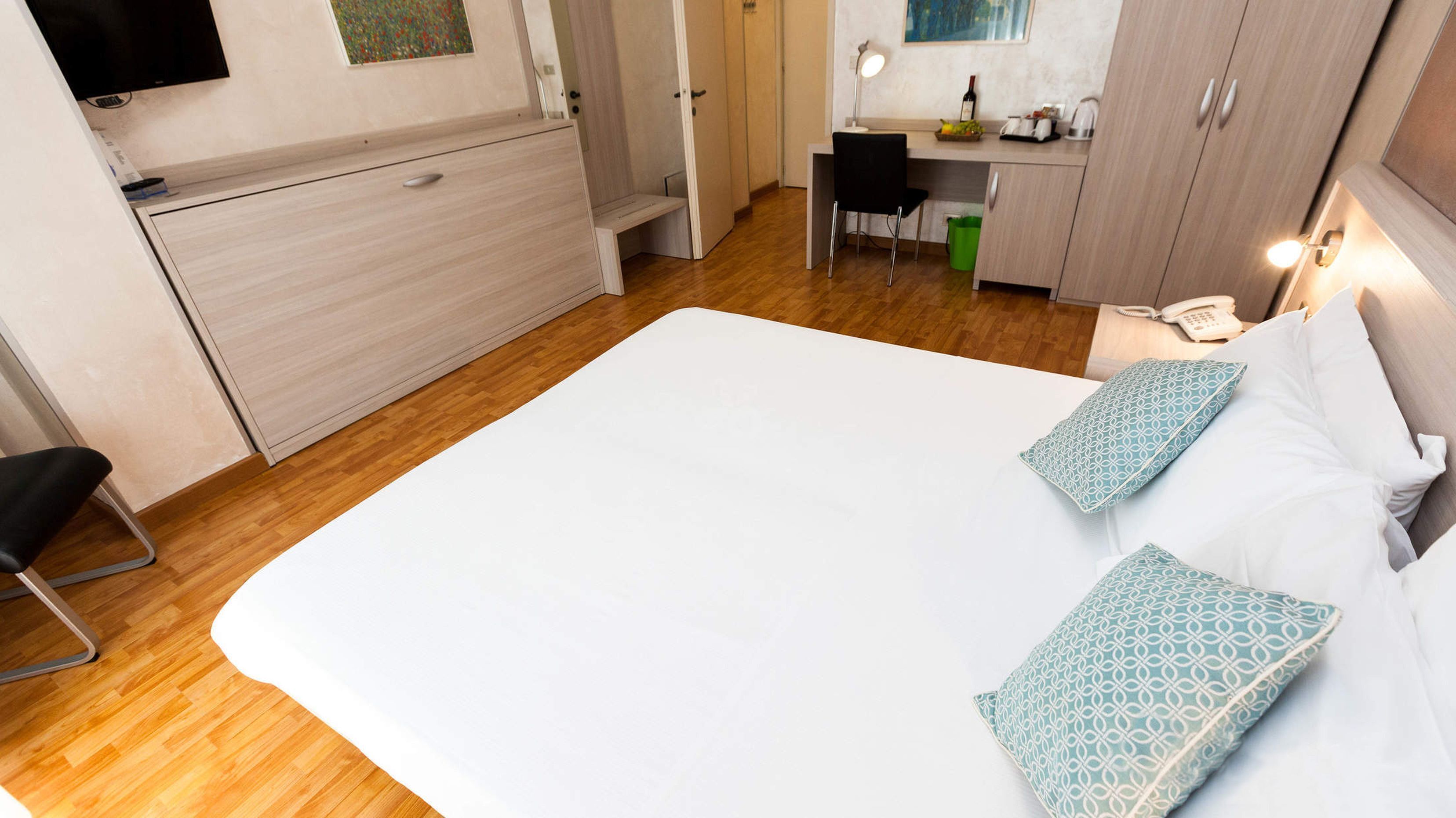 A compact hotel room with a bed, a desk, and a chair.