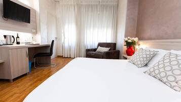 Een hotelkamer met een bed, een bureau, een stoel, een televisie en een vaas met bloemen.