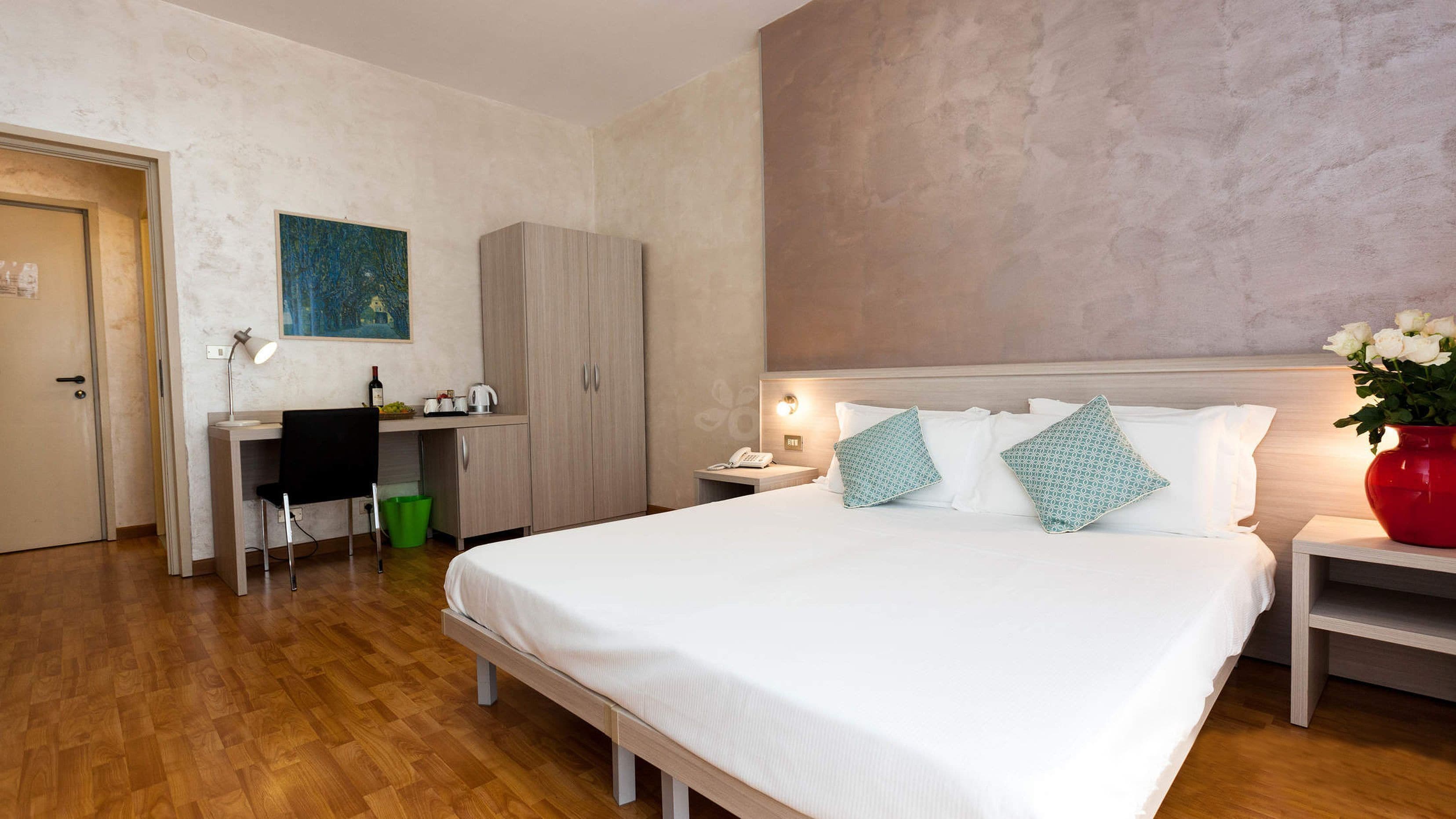 A hotel room with a bed, a desk, and a chair.