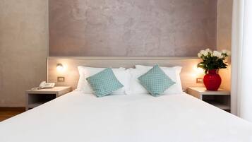 A hotel room with a large bed, two bedside tables, a phone, and a vase with flowers.