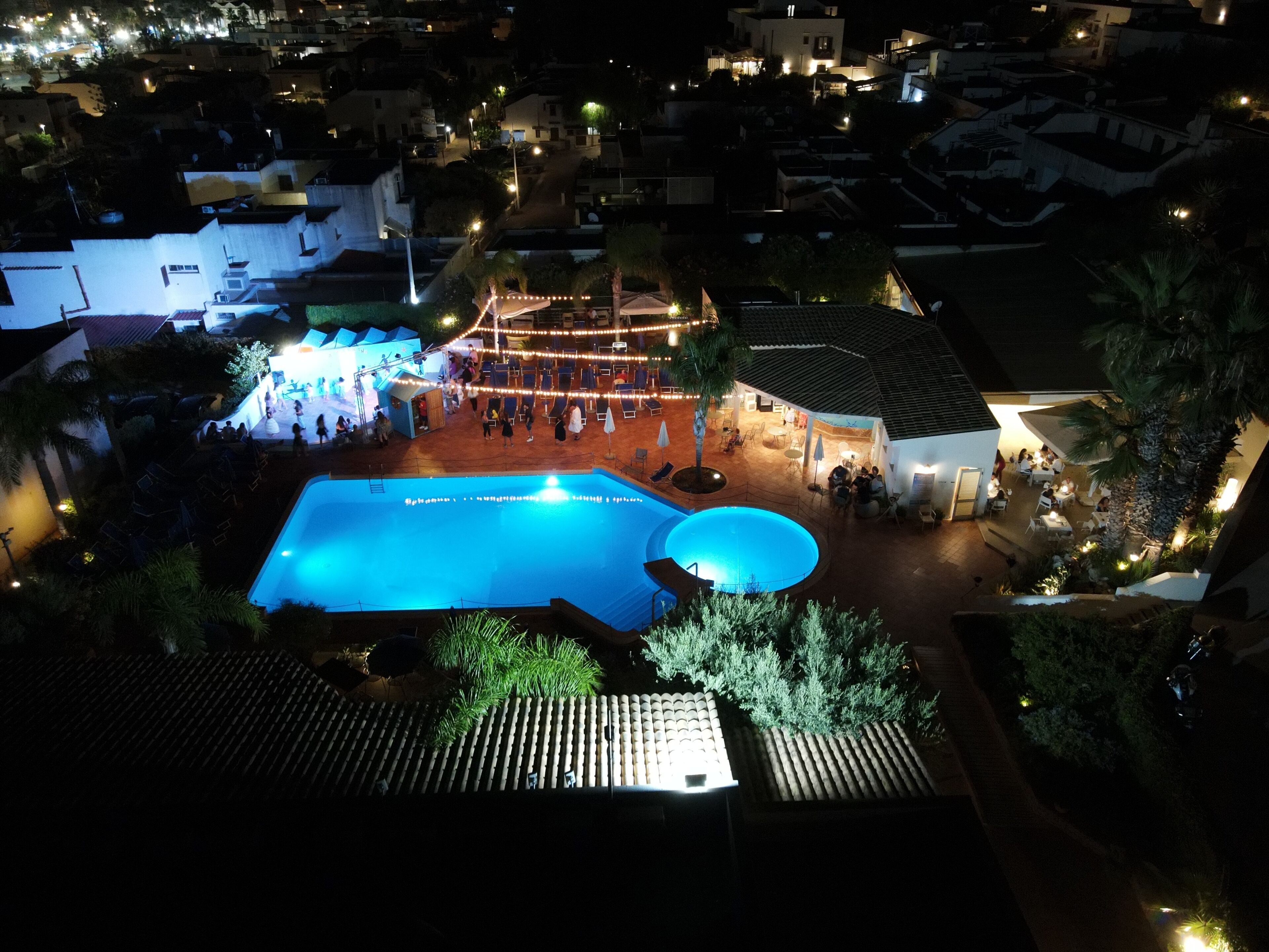 Un espace piscine sur le toit, comprenant une grande piscine, des sièges et une scène pour les événements.