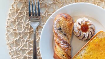 A plate with croissant, a pastry, and a piece of bread with cheese on a white plate.