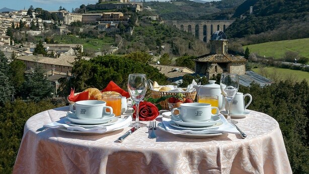 Una mesa dispuesta para el desayuno, con vistas a un pueblo histórico y un castillo al fondo.
