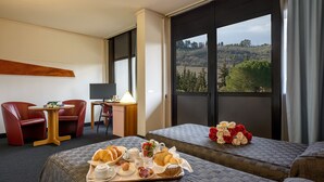 Habitación de hotel con dos camas, un escritorio con computadora, una silla y una mesa con artículos para el desayuno.