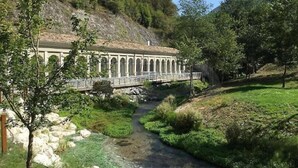 Un puente sobre un arroyo que conduce a un edificio con ventanas de arco.