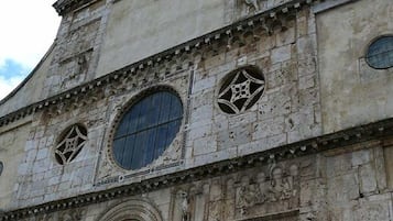 Um edifício histórico com detalhadas esculturas em pedra, uma entrada em arco imponente e janelas circulares.