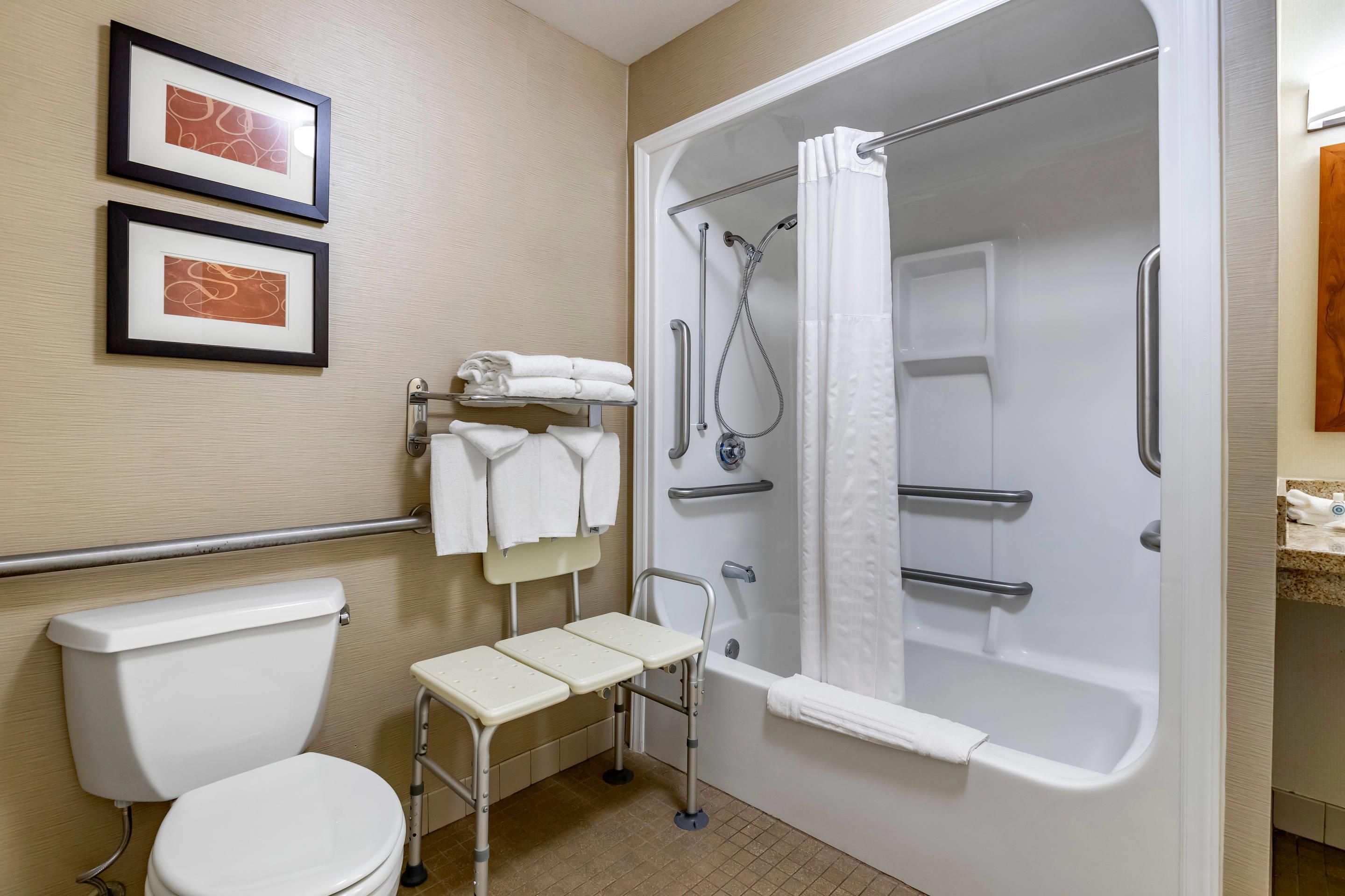 A bathroom with a white toilet, a shower with a glass door, and two framed pictures on the wall.