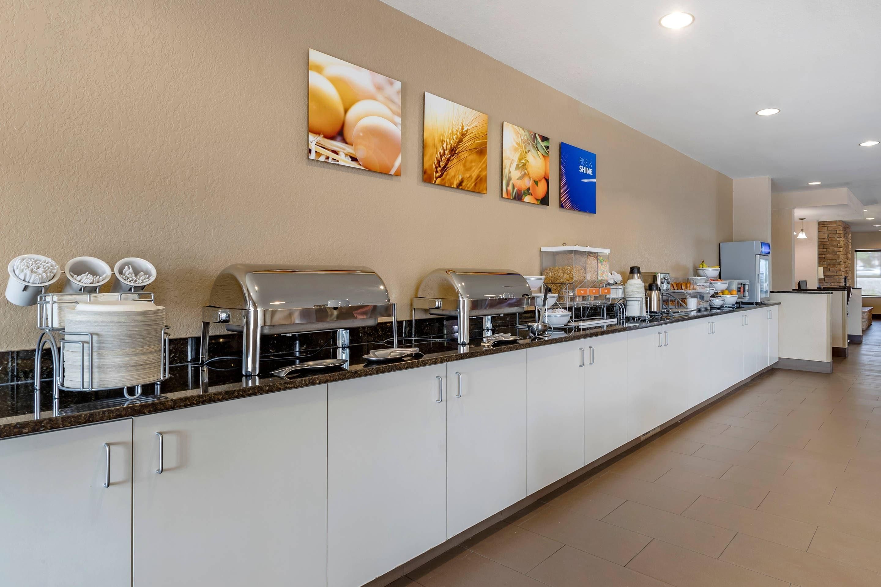A buffet setup with various food stations, a coffee machine, and a sign indicating a rice and shine option.