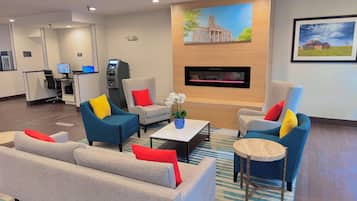 A hotel lobby with seating arrangements, a reception desk, and a fireplace.
