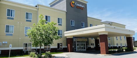A Comfort Suites hotel with a clear entrance, a parking lot, and a sign indicating handicapped parking.