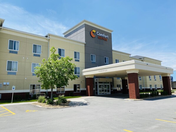 A Comfort Suites hotel with a clear entrance, a parking lot, and a sign indicating handicapped parking.