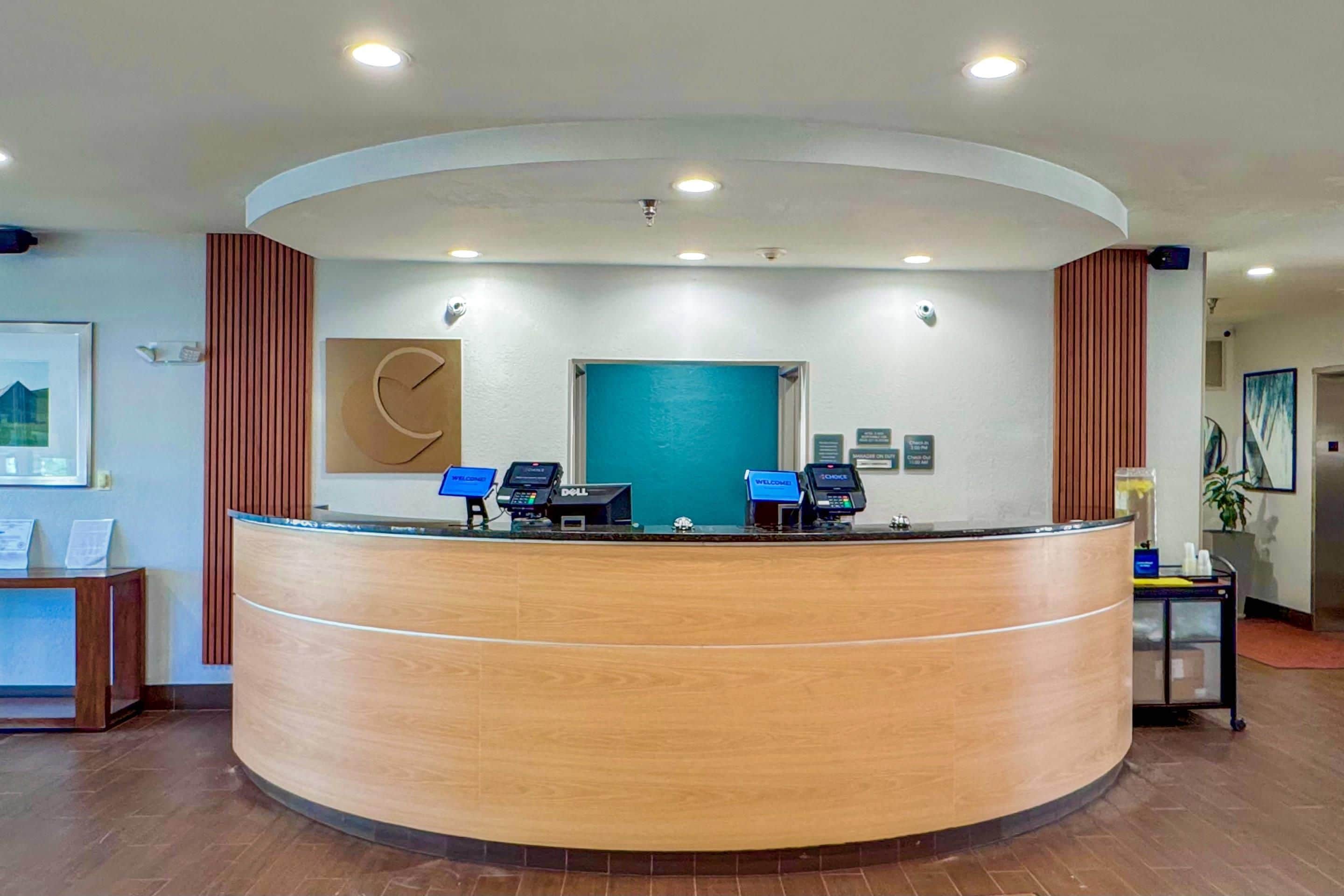 Uma receção com design curvo, duas estações de trabalho com computadores, uma parede azul e um relógio.
