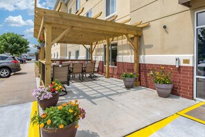 An outdoor patio area with a wooden pergola, seating, and potted plants. - Comfort Suites Coralville I-80 (Coralville)
