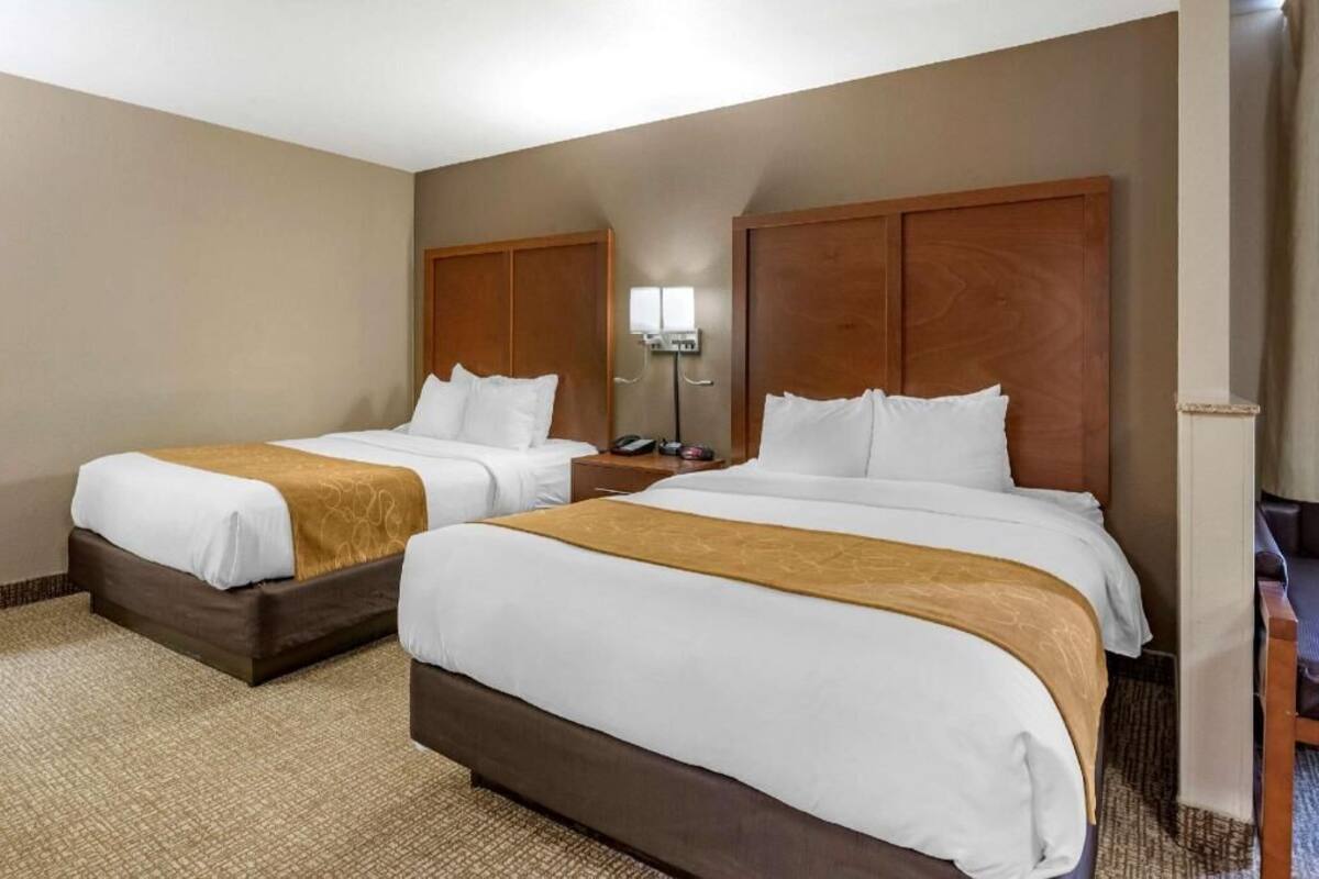 Una habitación de hotel con dos camas, una mesita de noche, una lámpara y una silla.